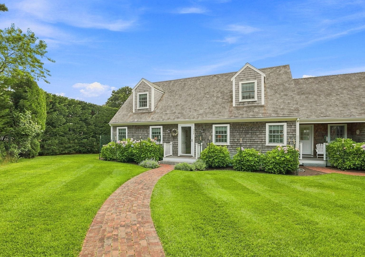 immaculate shingle-style home framed by mature lawn