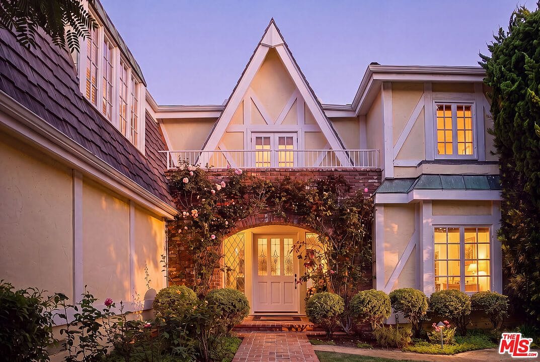 twilight front elevation, ivy-clad gable, windows lit
