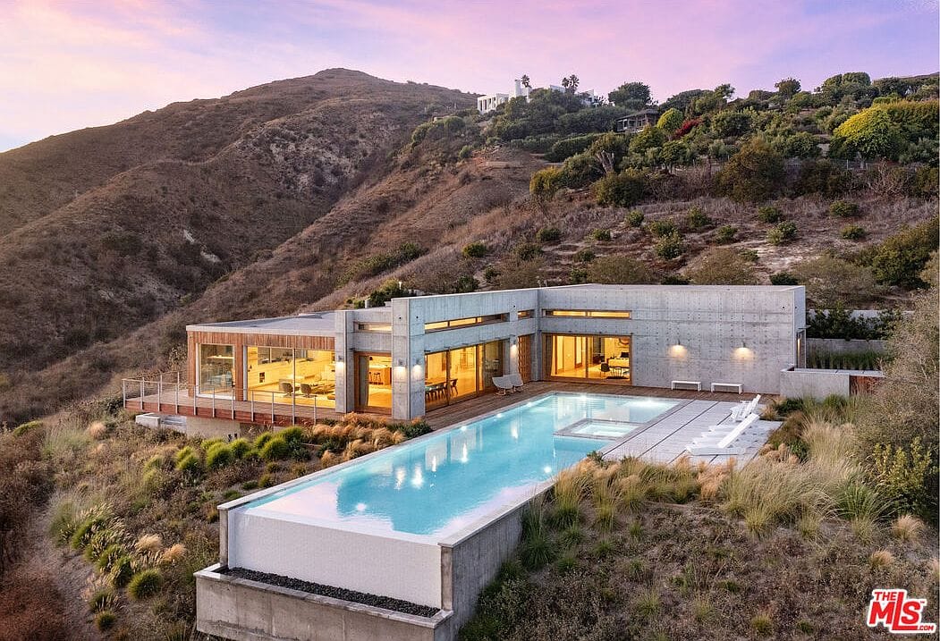 dusk aerial: poured-in-place concrete volumes and the 89’ infinity edge over the Pacific