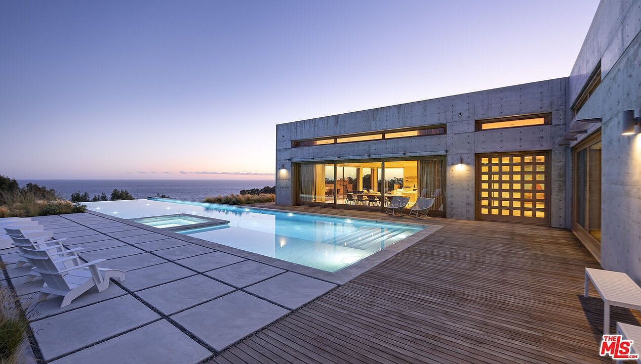 courtyard and pool at golden hour, walls of glass opened to the view