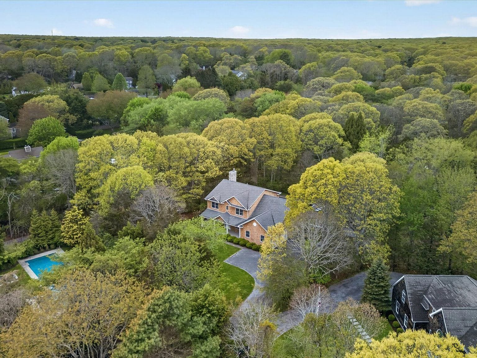 aerial view of the residence, pool, and wooded grounds